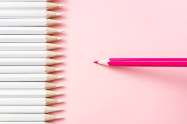 İş ve tasarım konsepti - beyaz kalem ve pembe kağıt arka plan üzerinde bir renk kalem çok. Liderlik, takım çalışması, başarı ve benzersiz sembolü.