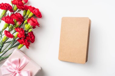 Kart ve hediye kutusu ile beyaz arka plan üzerinde izole kırmızı karanfil buketi