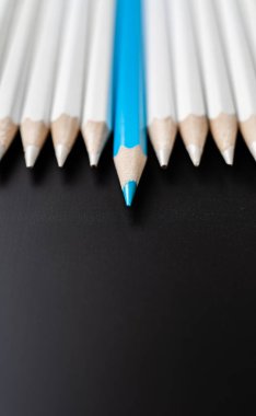 İş ve tasarım konsepti - beyaz kalem ve siyah arka plan üzerinde bir mavi renkli kalem çok. Liderlik, takım çalışması, başarı ve benzersiz sembolü.