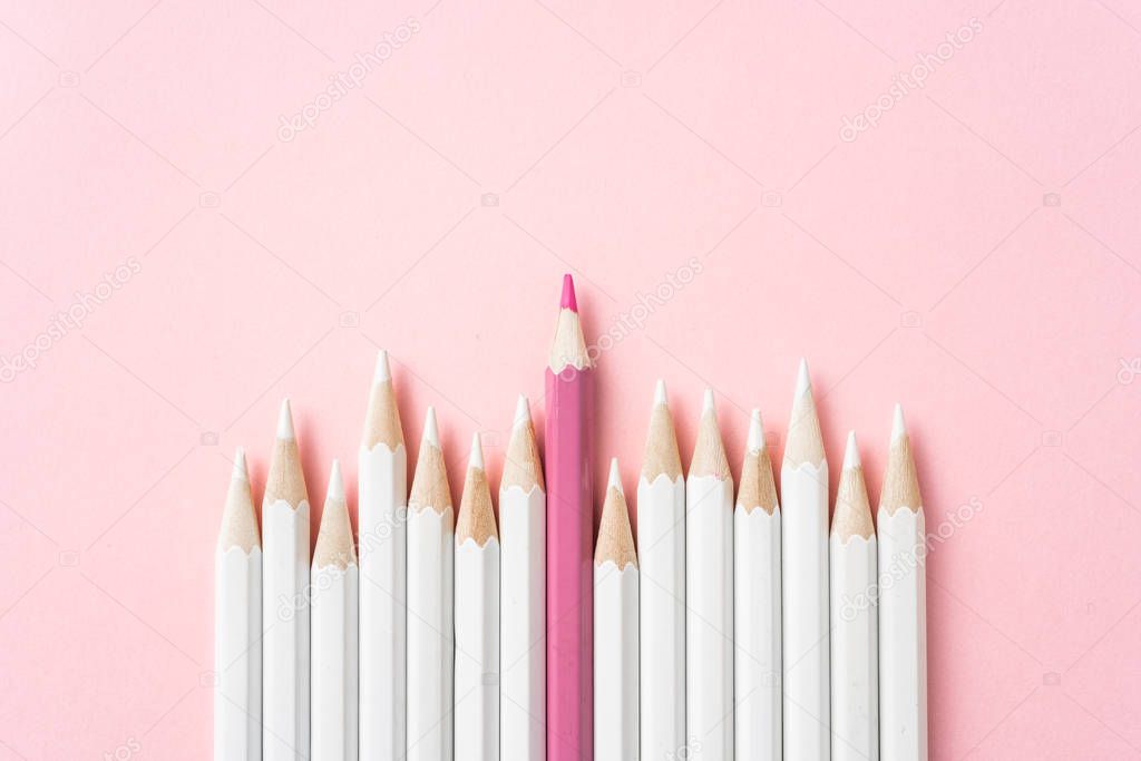 Business and design concept - lot of white pencils and one color pencil on pink paper background. Symbol of leadership, teamwork, success and unique.