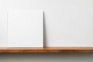 Kitaplık ta kare beyaz defter ve mockup için beyaz duvar