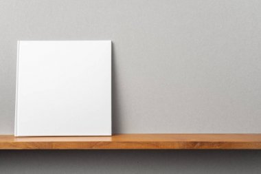 Tasarım konsepti - kitaplıkta kare beyaz dizüstü bilgisayarın ön görünümü ve mockup için gri duvar