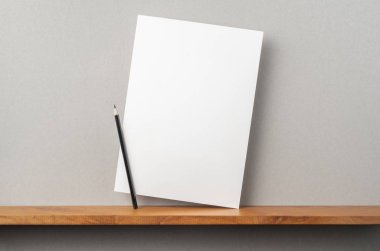 Maket için kitaplık ve gri duvar üzerinde duran kalem ile A4 sert kağıt
