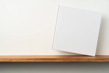 Kitaplık ta kare beyaz defter ve mockup için beyaz duvar