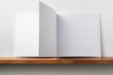 Kitaplık ta kare beyaz defter ve mockup için beyaz duvar