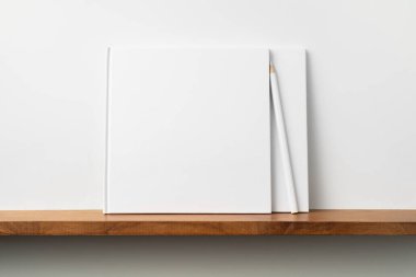 Kitaplıkta kalem ile kare beyaz defterler, mockup.