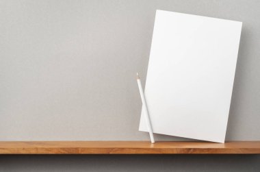 Maket için kitaplık ve gri duvar üzerinde duran kalem ile A4 sert kağıt