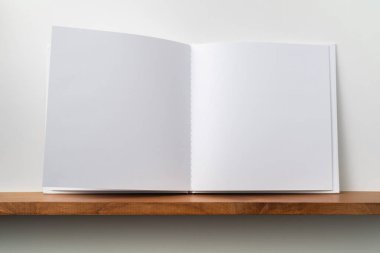 Kitaplık ta kare beyaz defter ve mockup için beyaz duvar