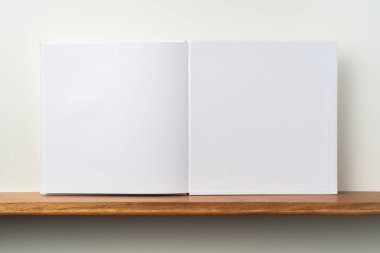 Kitaplık ta kare beyaz defter ve mockup için beyaz duvar