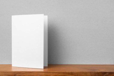 Mockup için kitaplık ve gri duvar da tebrik kartı ön görünümü.
