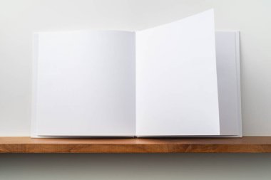 Kitaplık ta kare beyaz defter ve mockup için beyaz duvar