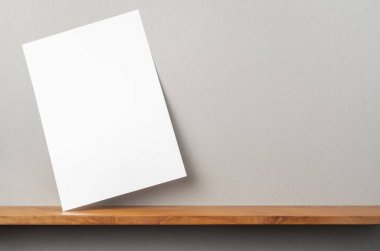 Maket için kitaplık ve gri duvar üzerinde duran A4 kağıt ön görünümü