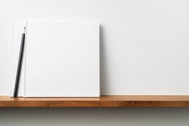 Kitaplıkta kalem ile kare beyaz defterler, mockup.