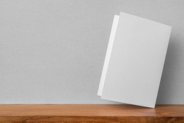 Mockup için kitaplık ve gri duvar da tebrik kartı ön görünümü.