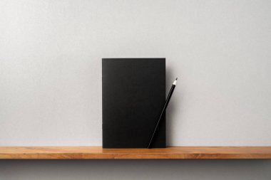 Maket için kitaplık ve gri duvar üzerinde duran kalem ile Siyah dergi