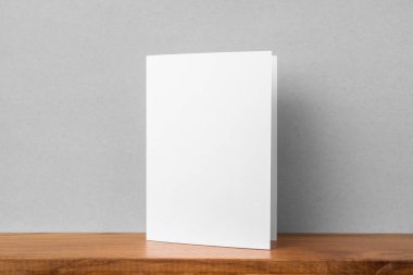 Mockup için kitaplık ve gri duvar da tebrik kartı ön görünümü.