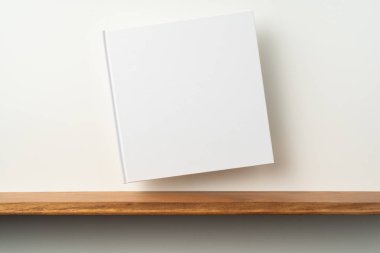 Kitaplık ta kare beyaz defter ve mockup için beyaz duvar