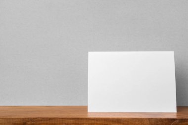 Mockup için kitaplık ve gri duvar da tebrik kartı ön görünümü.