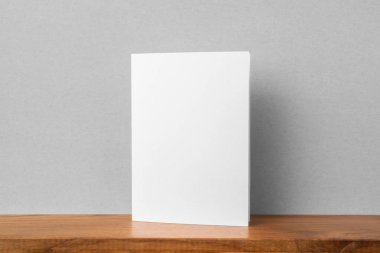Mockup için kitaplık ve gri duvar da tebrik kartı ön görünümü.