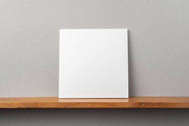 Tasarım konsepti - kitaplıkta kare beyaz dizüstü bilgisayarın arka görünümü ve mockup için gri duvar