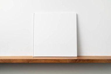 Kitaplık ta kare beyaz defter ve mockup için beyaz duvar
