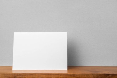 Mockup için kitaplık ve gri duvar da tebrik kartı ön görünümü.