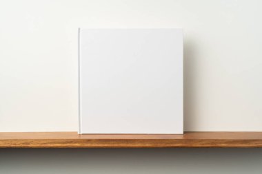 Kitaplık ta kare beyaz defter ve mockup için beyaz duvar