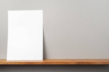 Maket için kitaplık ve gri duvar üzerinde duran A4 kağıt ön görünümü