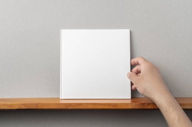 Erkek el tutma kare beyaz defter kitaplık ve mockup için gri duvar
