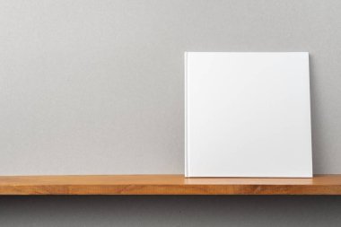 Tasarım konsepti - kitaplıkta kare beyaz dizüstü bilgisayarın ön görünümü ve mockup için gri duvar