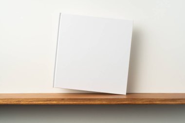 Kitaplık ta kare beyaz defter ve mockup için beyaz duvar