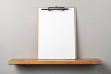 Kitapçık ve gri duvar üzerinde pano ve kalem ile A4 kağıt ön görünümü mockup için