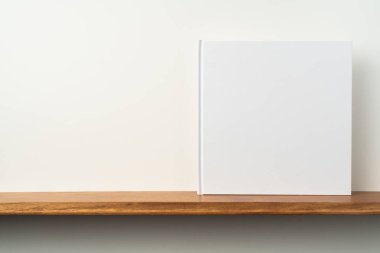 Kitaplık ta kare beyaz defter ve mockup için beyaz duvar