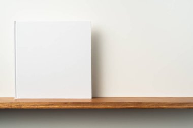 Kitaplık ta kare beyaz defter ve mockup için beyaz duvar