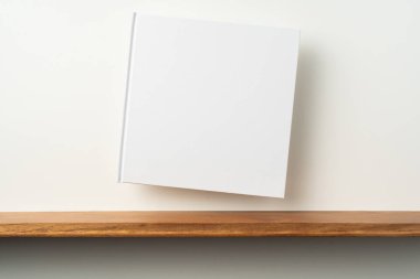 Kitaplık ta kare beyaz defter ve mockup için beyaz duvar
