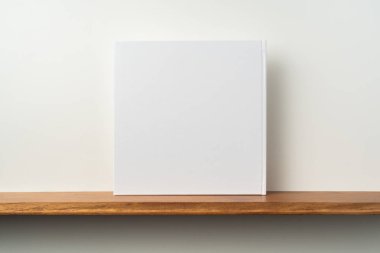 Kitaplık ta kare beyaz defter ve mockup için beyaz duvar