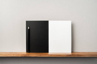 Maket için kitaplık ve gri duvar üzerinde duran kalem ile Siyah dergi