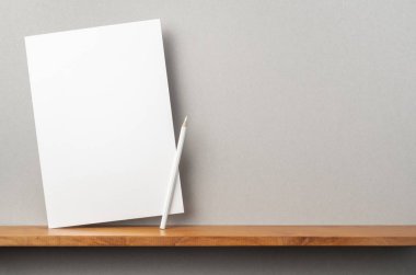 Maket için kitaplık ve gri duvar üzerinde duran kalem ile A4 sert kağıt