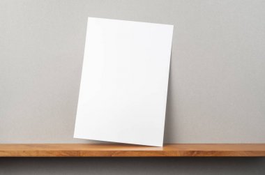 Maket için kitaplık ve gri duvar üzerinde duran A4 kağıt ön görünümü