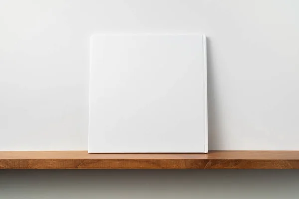 モックアップ用の本棚と白い壁の正方形の白いノートブック — ストック写真