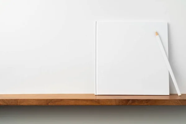 Cuadrado Cuaderno Blanco Con Lápiz Estantería Pared Blanca Para Maqueta —  Fotos de Stock