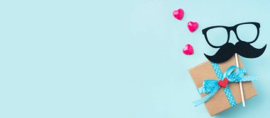 Hediye kutusu ile Babalar gün düzeni, gözlük ve bıyık silueti, pembe kalpler, mockup için kopya alanı.