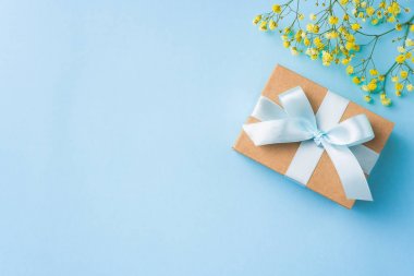Şerit kraft hediye kutusu, mavi arka plan üzerinde sarı çiçekler, mock up için kopya alanı.