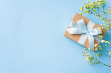 Şerit kraft hediye kutusu, mavi arka plan üzerinde sarı çiçekler, mock up için kopya alanı.
