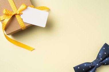 Sarı arka plan üzerinde etiket ve papyon ile sarı kurdele kraft hediye kutusu ile babalar günü düzeni üst görünümü