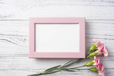 Anne gün mockup için beyaz Vintage ahşap arka plan üzerinde fotoğraf çerçevesi ile pembe karanfil çiçekler üst görünümü