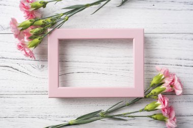 Anne gün mockup için beyaz Vintage ahşap arka plan üzerinde fotoğraf çerçevesi ile pembe karanfil çiçekler üst görünümü