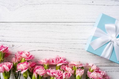 Beyaz Vintage ahşap arka planda hediye kutusu ile pembe karanfil çiçekler