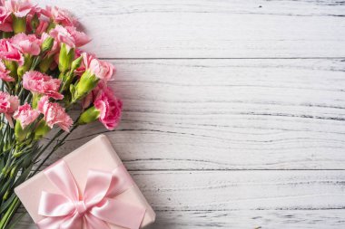 Beyaz Vintage ahşap arka planda hediye kutusu ile pembe karanfil çiçekler