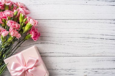 Beyaz Vintage ahşap arka planda hediye kutusu ile pembe karanfil çiçekler
